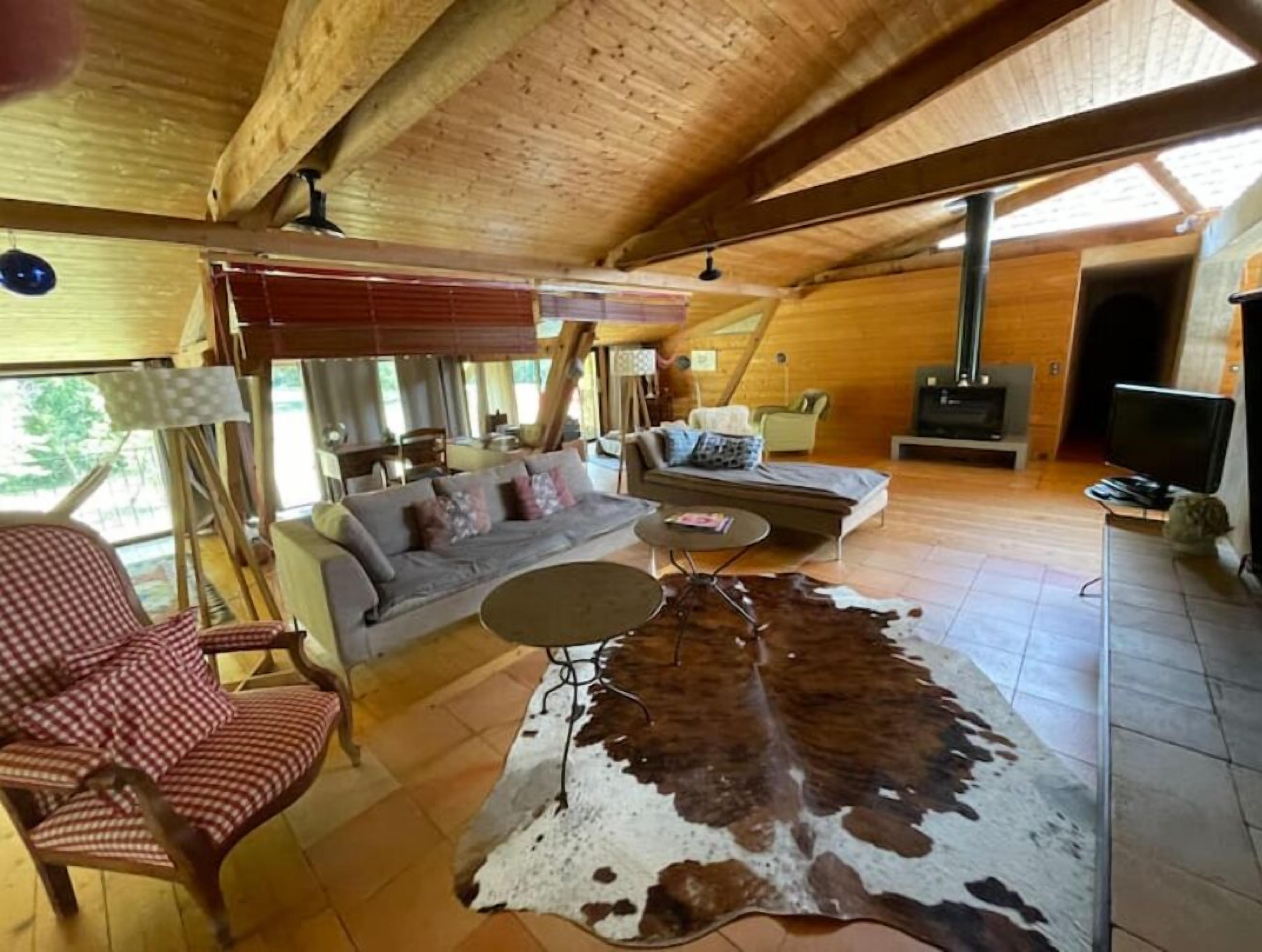 Ein geräumiges Wohnzimmer mit einer großen Ledersofa, einem Couchtisch und einem Fernseher. Ein Kamin und ein Fenster mit Jalousien sind ebenfalls vorhanden.