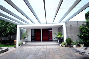 Stylish entrance with a flat roof, large doors, and lush greenery.