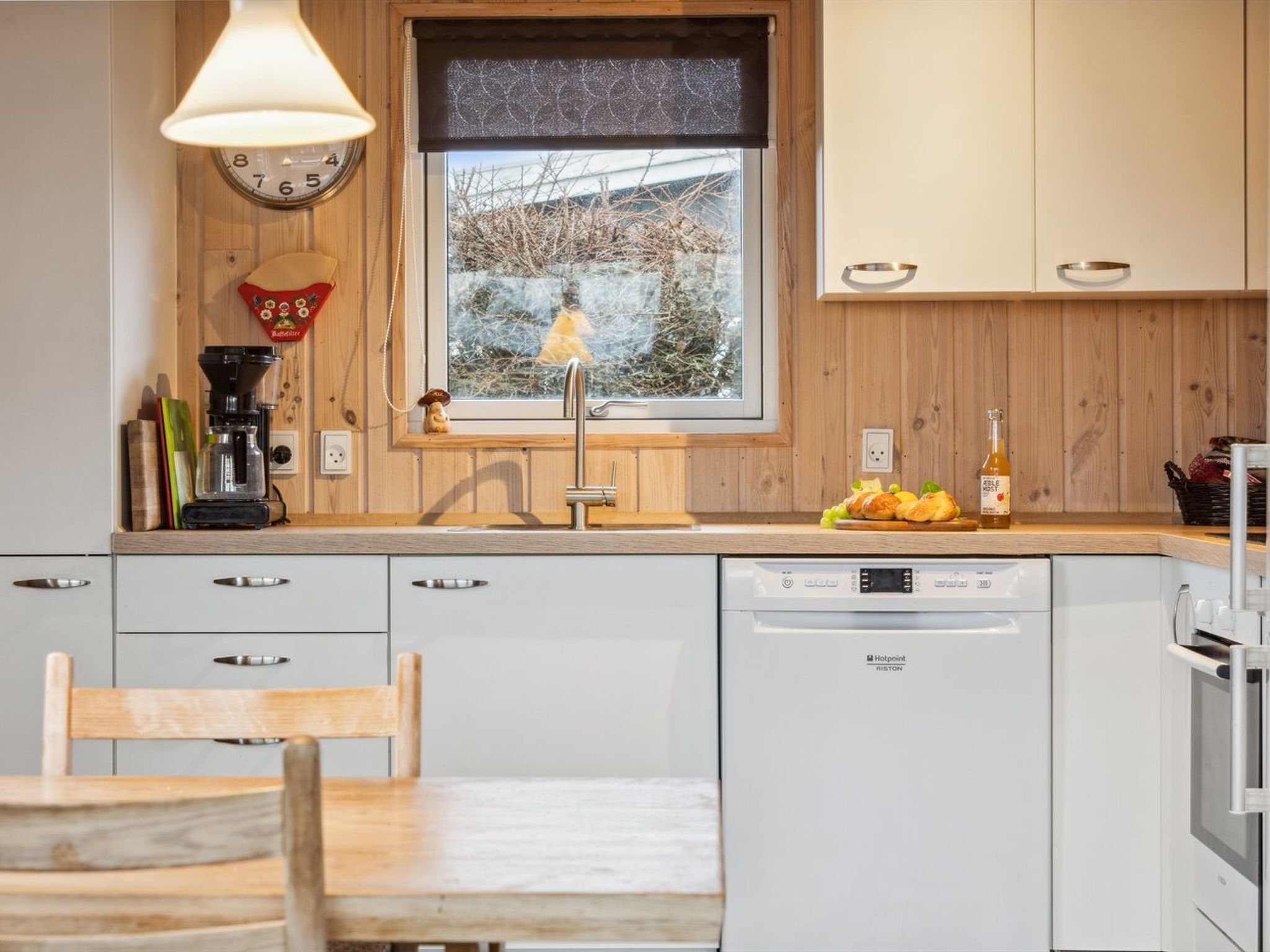 Una cocina moderna con encimera de madera, lavavajillas integrado y ventana con vistas a árboles.