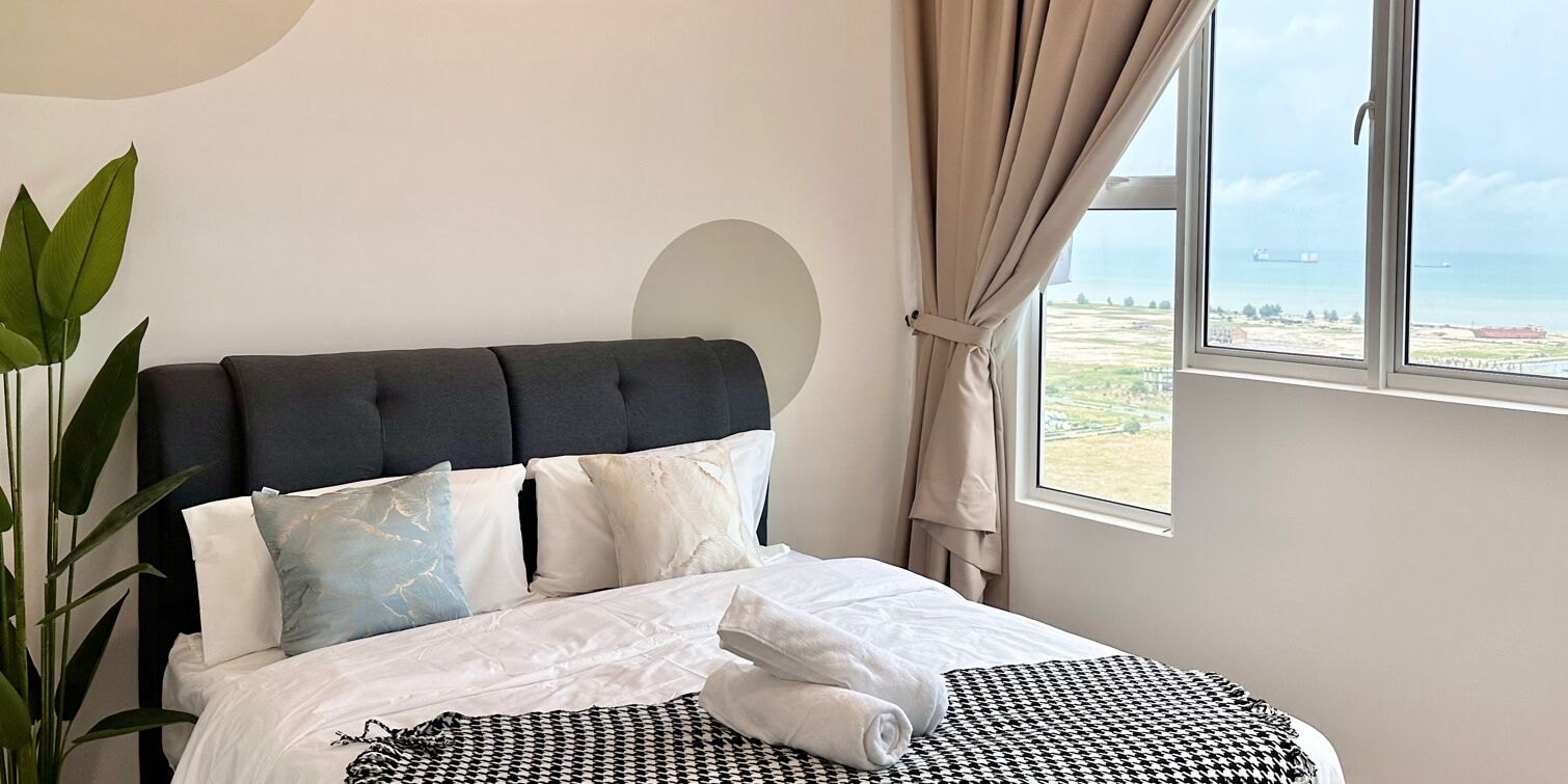 Un dormitorio con cama, vista al mar y una planta.