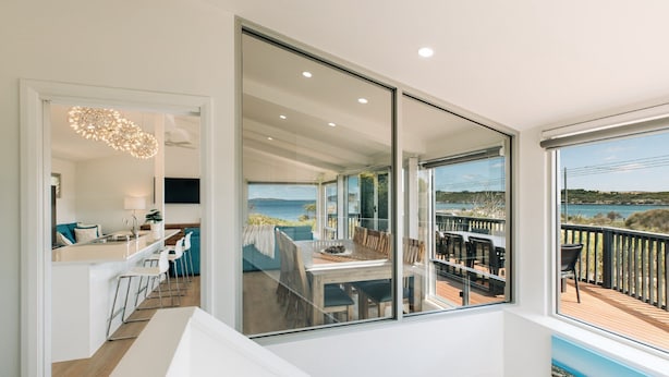 Et moderne interiør med spiseområde, køkken og en balkon med havudsigt.