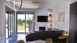 A modern living room with a sofa, TV, fireplace, and dining area with chairs and a table.