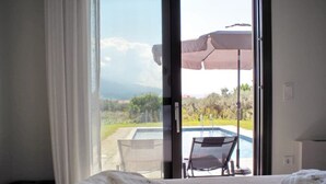 A hotel room with a bed, a chair, and a view of an outdoor swimming pool.