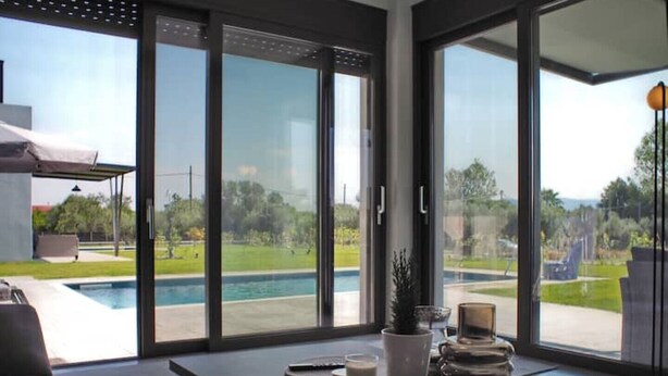 A modern living room with a large sliding glass door leading to a pool area.