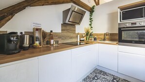 Una cocina moderna con armarios blancos, encimera de madera, horno empotrado y campana extractora de acero inoxidable.