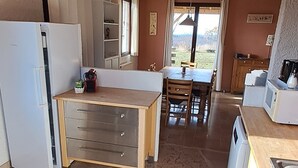 Een keuken met een houten plafond, een eettafel en een koelkast.