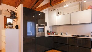 Une cuisine moderne avec des appareils électroménagers noirs, des armoires blanches et un plancher en bois.