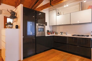 Una cocina moderna con electrodomésticos negros, armarios blancos y suelo de madera.