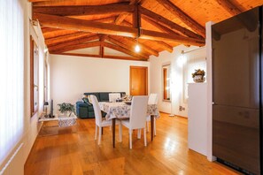 Un espace repas doté d’un plafond en bois, d’une table à manger avec des chaises, d’un canapé et d’un réfrigérateur.