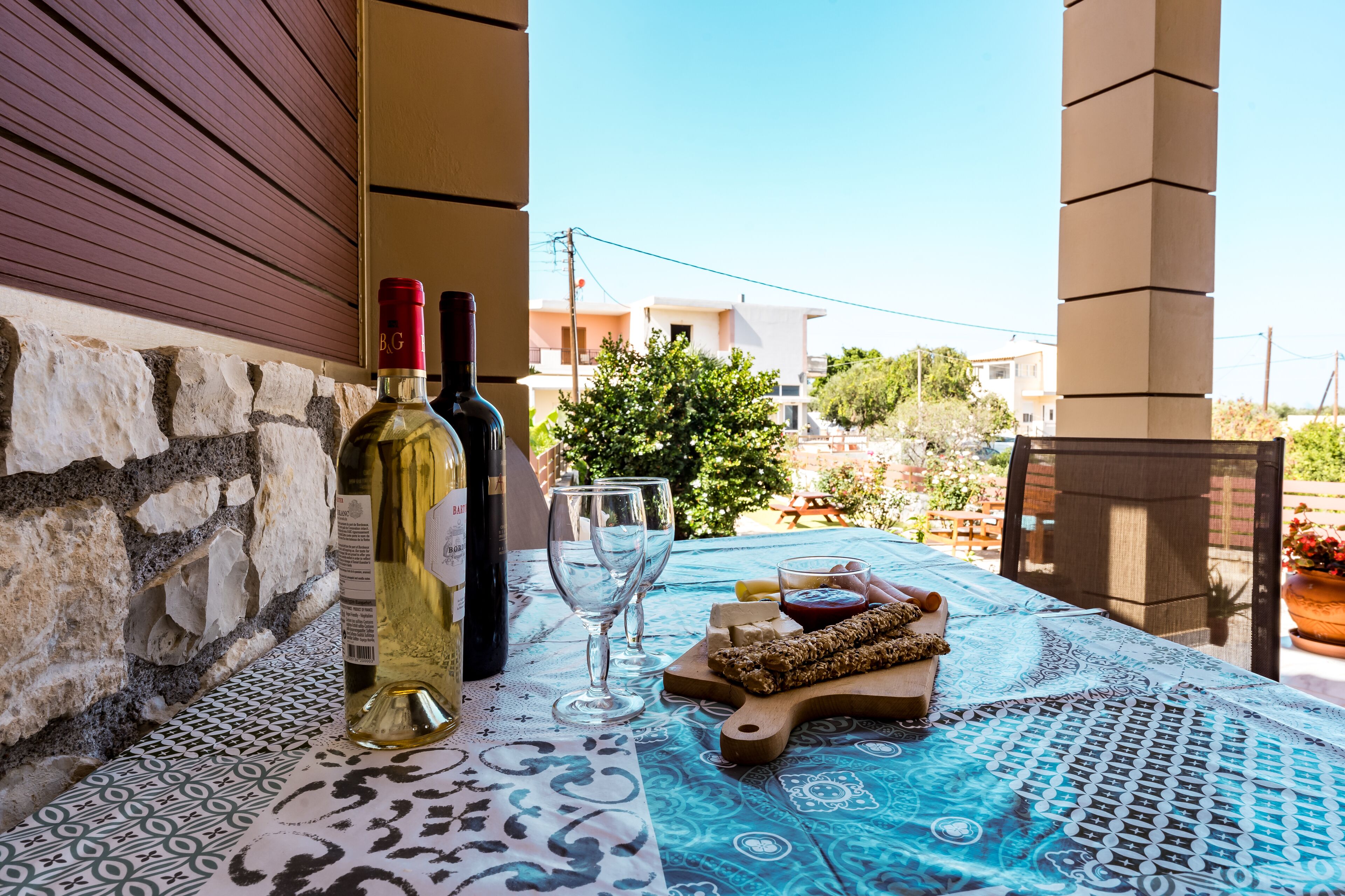 A table set with wine bottles, glasses, and a wooden board with bread and cheese.