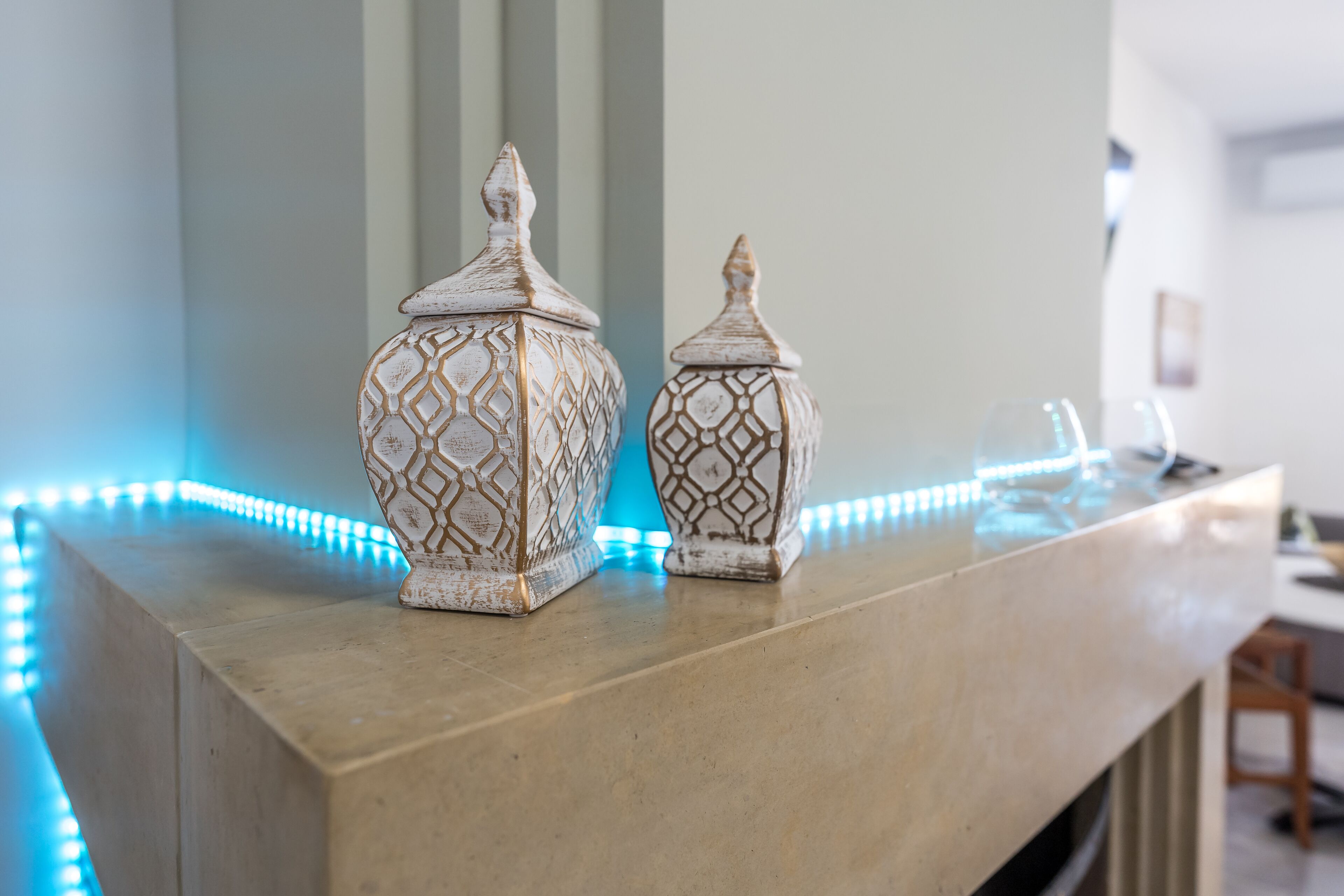 Two decorative vases on a marble countertop with blue LED lights.