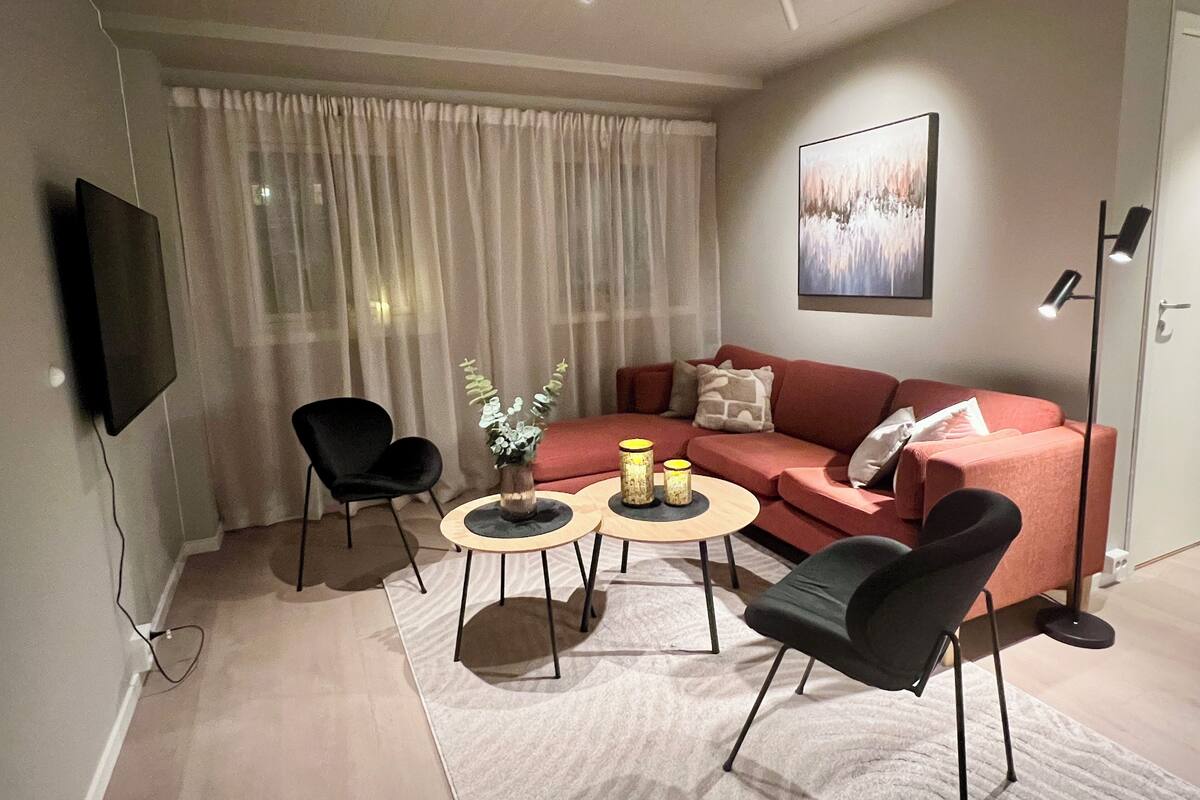 A modern living room with a sofa, two chairs, a coffee table, and a flat-screen TV.