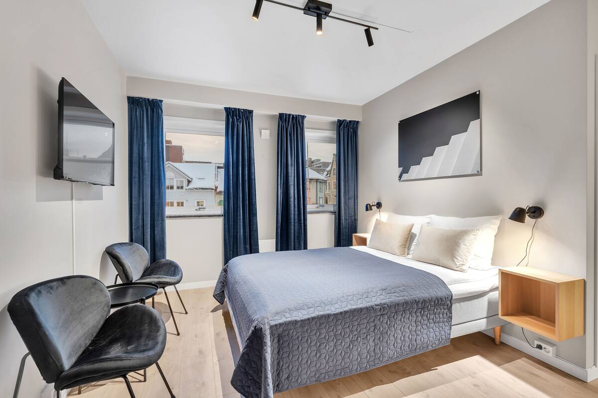 A modern bedroom with a bed, a desk, and a chair.