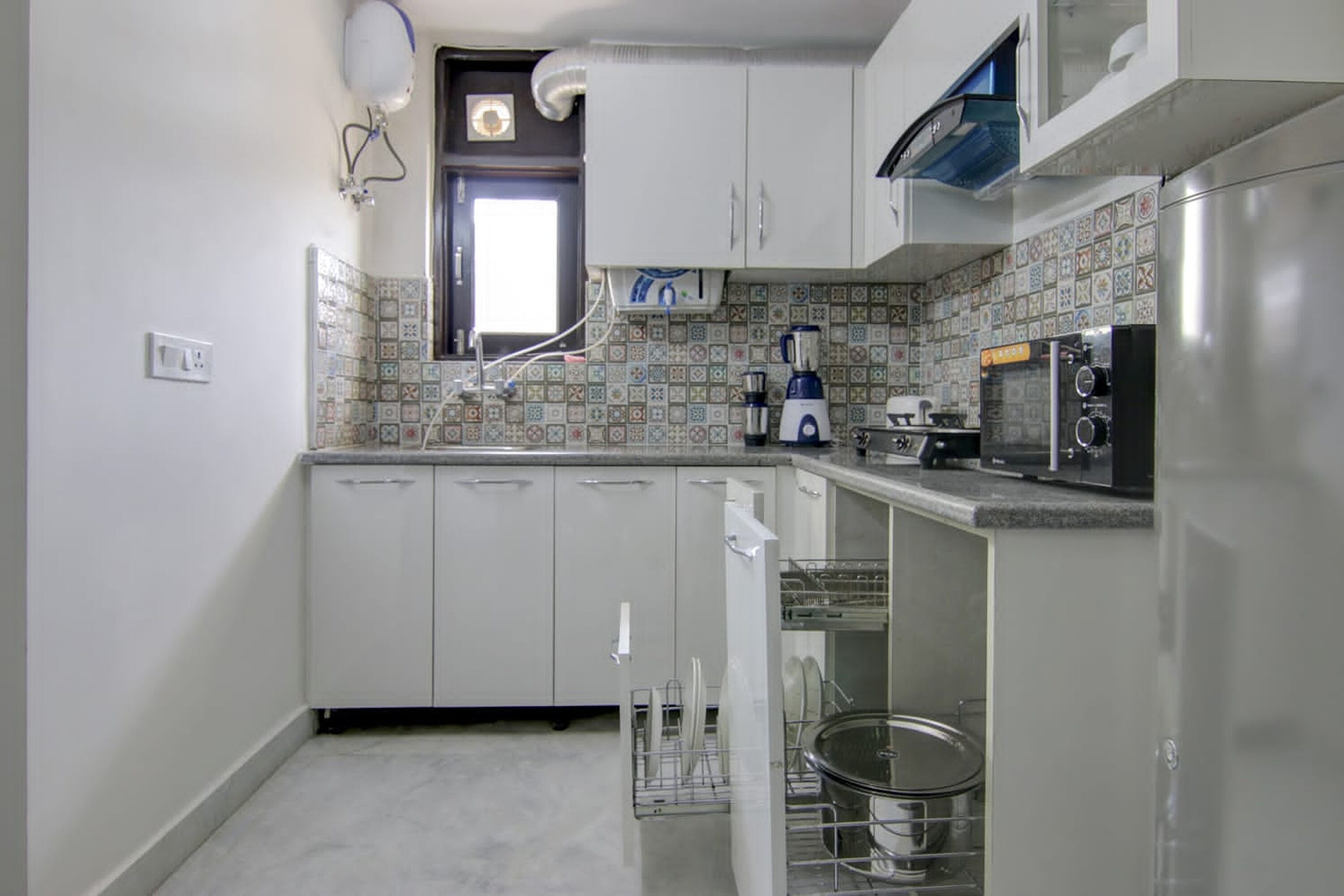 A compact kitchen with white cabinets, a built-in dishwasher, a blender, and a microwave.