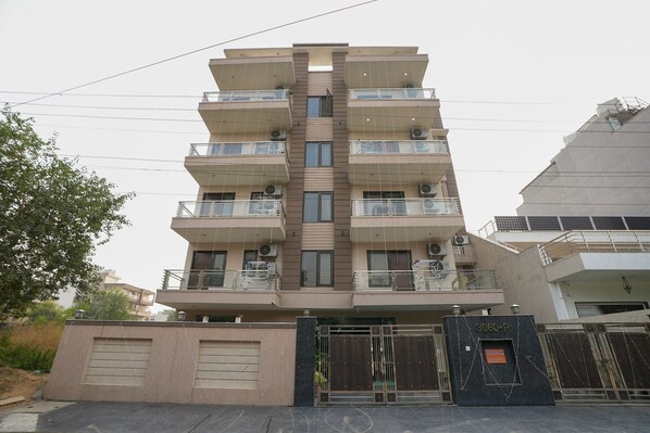 Stylish residential building with a central vertical strip, offering balconies and air conditioning units.