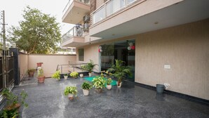 Un patio con plantas en macetas, un tapete verde y un cubo de metal.