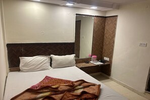 A hotel room with a bed, a bedside table, a mirror, and a wardrobe. - Shree Lodge Near New Delhi Railway Station, Paharganj (New Delhi)