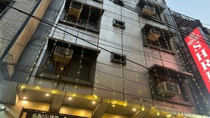A building with multiple balconies and a sign for 'Shree Lodge' indicating a room with homely comforts.