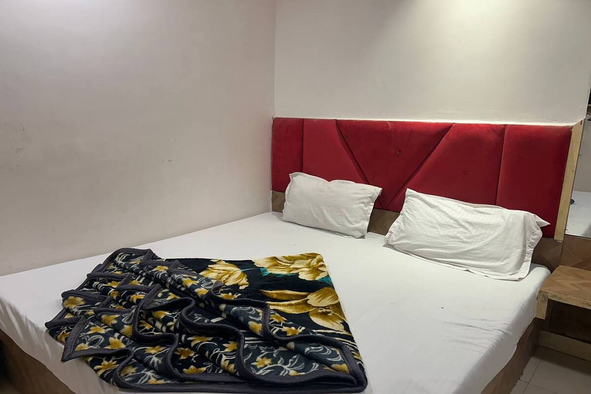 Una cama con cabecera roja, almohadas blancas y una colcha estampada.