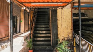 A hotel entrance with a staircase, potted plants, and a signboard advertising lodging and boarding services. - Hotel Sai Parikrama (Navi Mumbai)