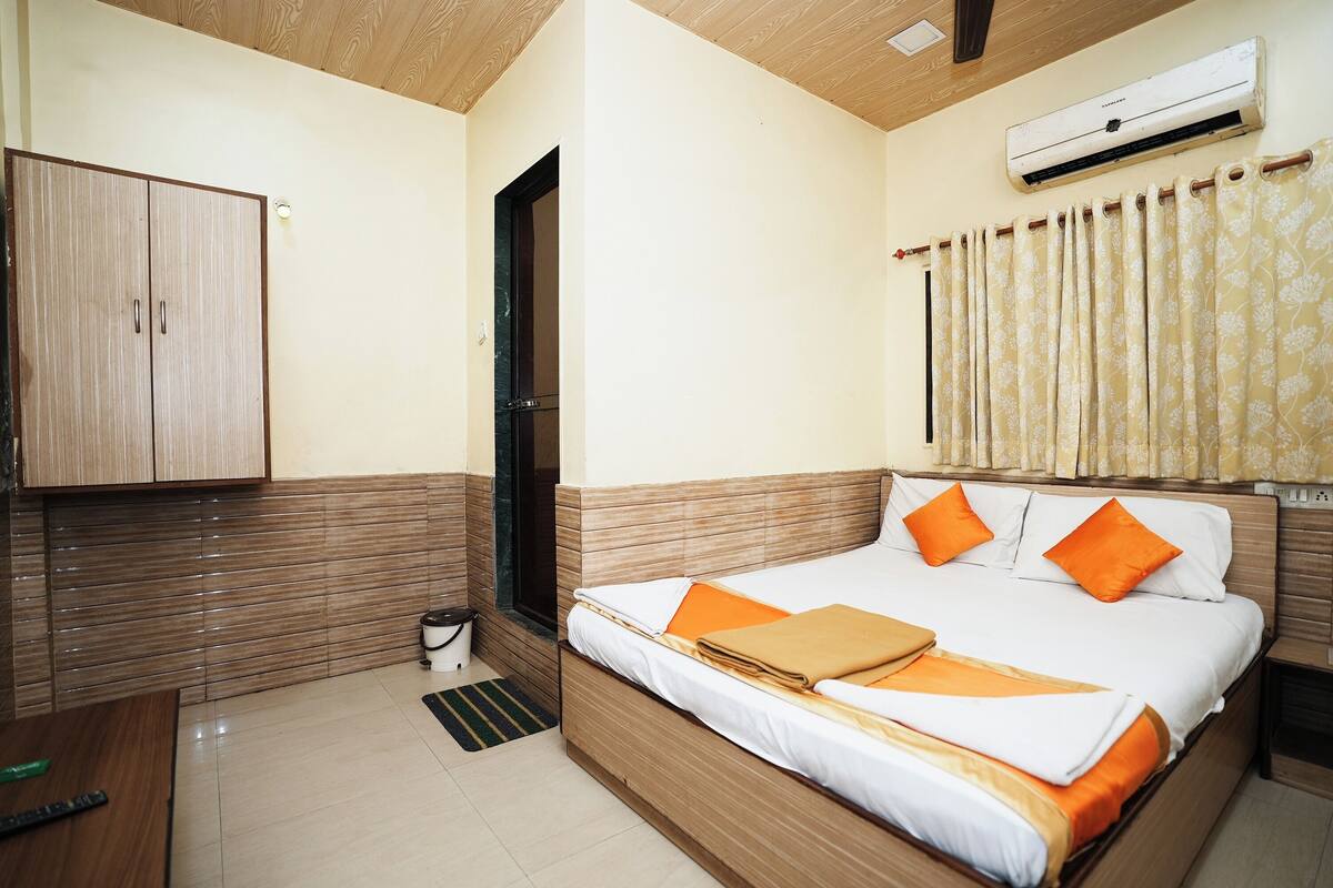 A hotel room with a bed, wardrobe, and an air conditioning unit.