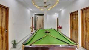A pool table in a hallway with wooden doors and a ceiling fan. - Hotel Grand (New Delhi)