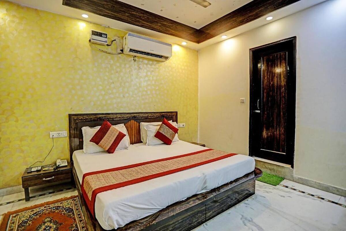 A bedroom with a bed, bedside table, and an air conditioning unit on the wall.