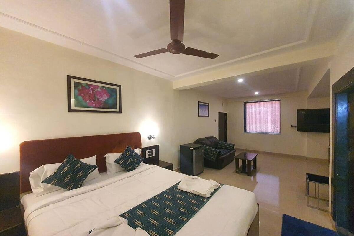 Ein Hotelzimmer mit Bett, Schreibtisch, Stuhl, Fernseher und Deckenventilator.