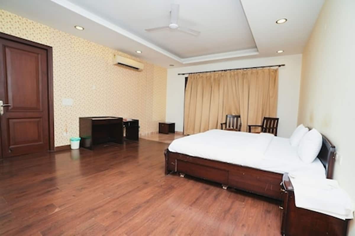 A bedroom with a large bed, a desk, a chair, and a wardrobe.