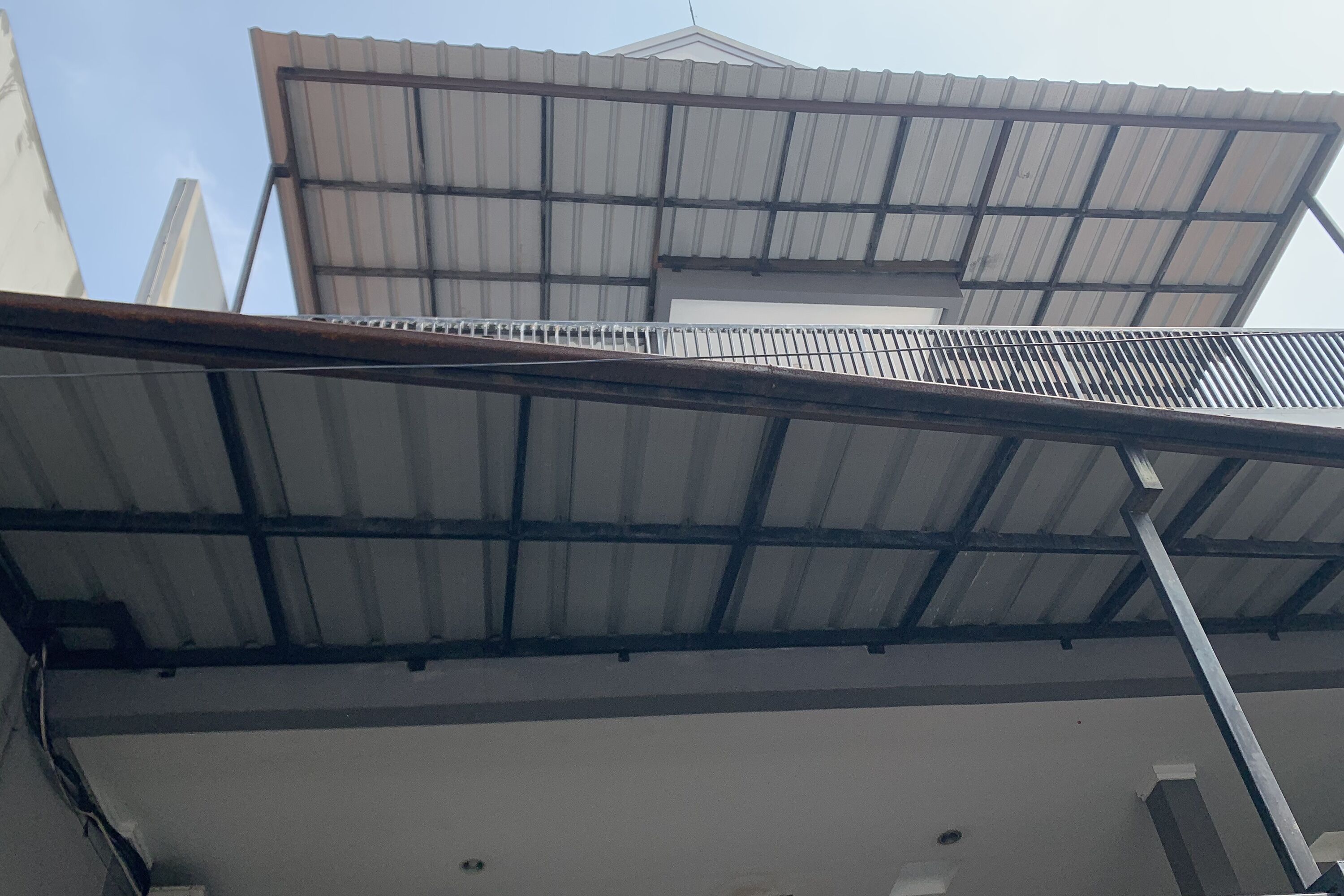Un edificio con techo de lámina metálica y fachada blanca.