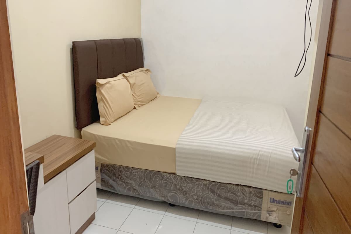 A small, neatly arranged bedroom with a bed, a bedside table, and a wardrobe.