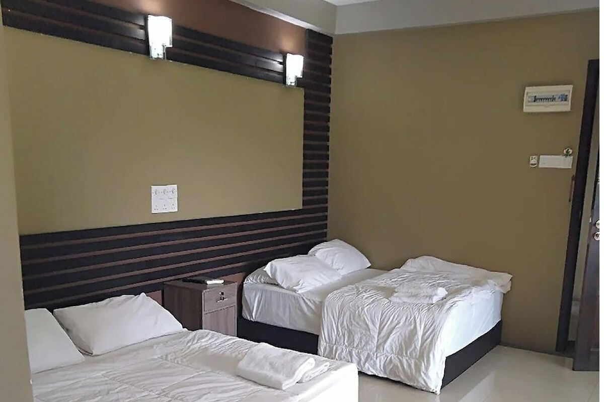 Ein Hotelzimmer mit zwei Betten, einem Holzkopfende, einem Nachttisch und einer Wandleuchte.
