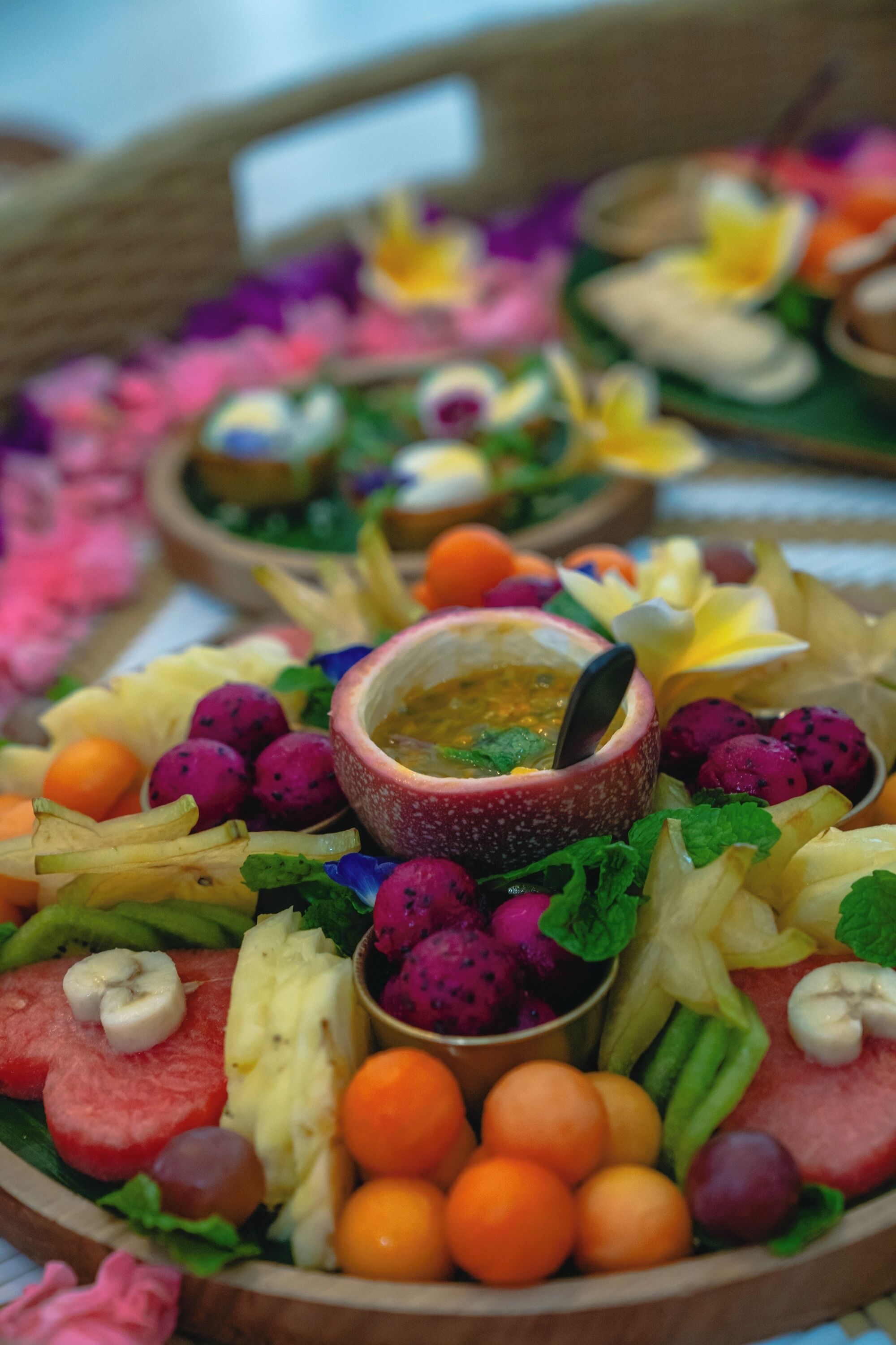 A fruit platter with various fruits and a small bowl of sauce.