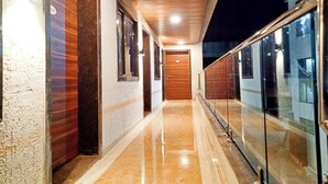 A corridor with a wooden ceiling, glass doors, and a marble floor. - Hotel Sai Executive Near Holy Cross Church Mahabaleshwar (Mahabaleshwar)