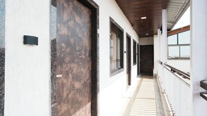 A corridor with a large metal door, windows, and a wooden ceiling. - Hotel Sai Executive Near Holy Cross Church Mahabaleshwar (Mahabaleshwar)