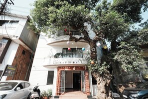 A hotel entrance with a balcony, a tree in front, and a signboard. - Hotel Maharaja Residency (Mahabaleshwar)
