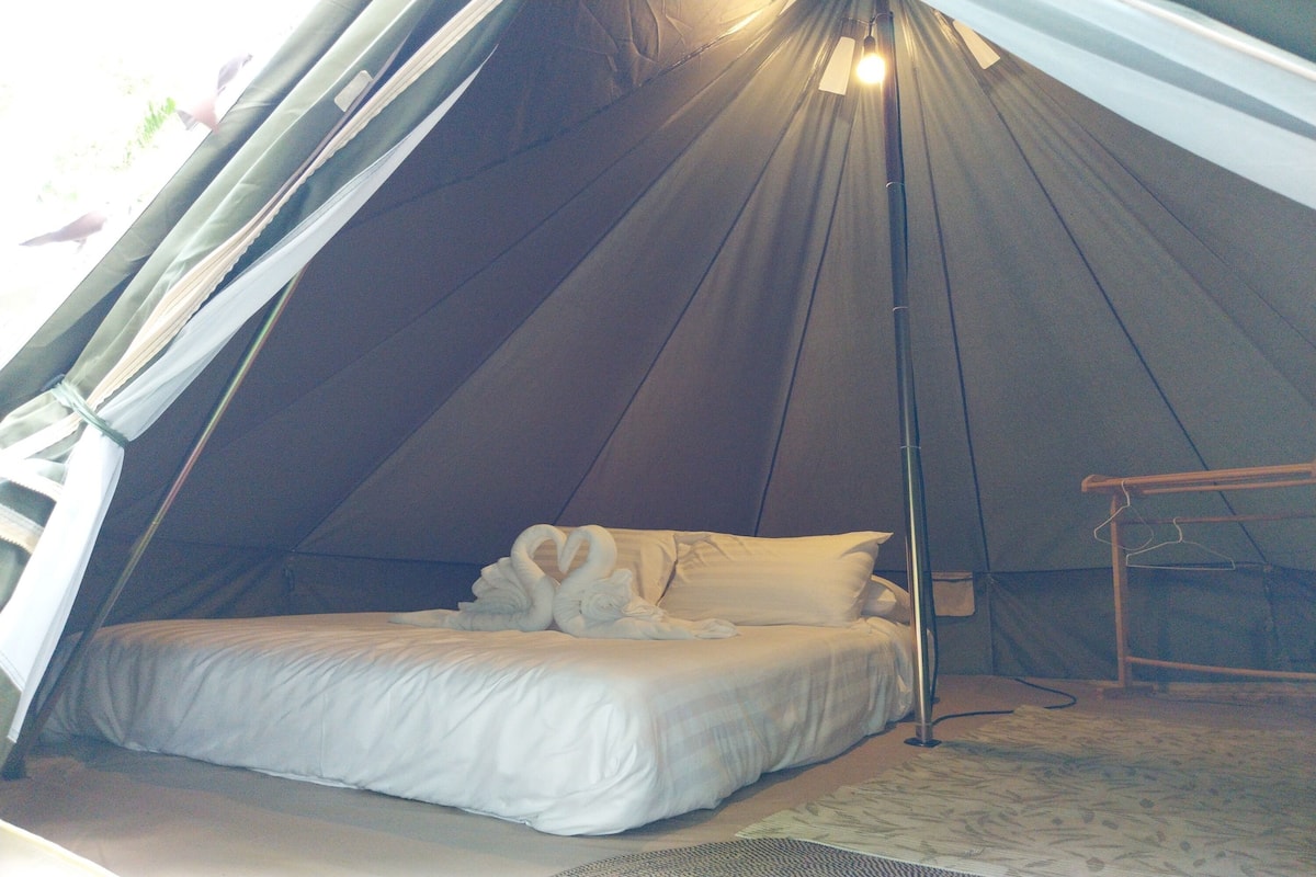 Una tenda amb un llit, almoines i una làmpada penjant.