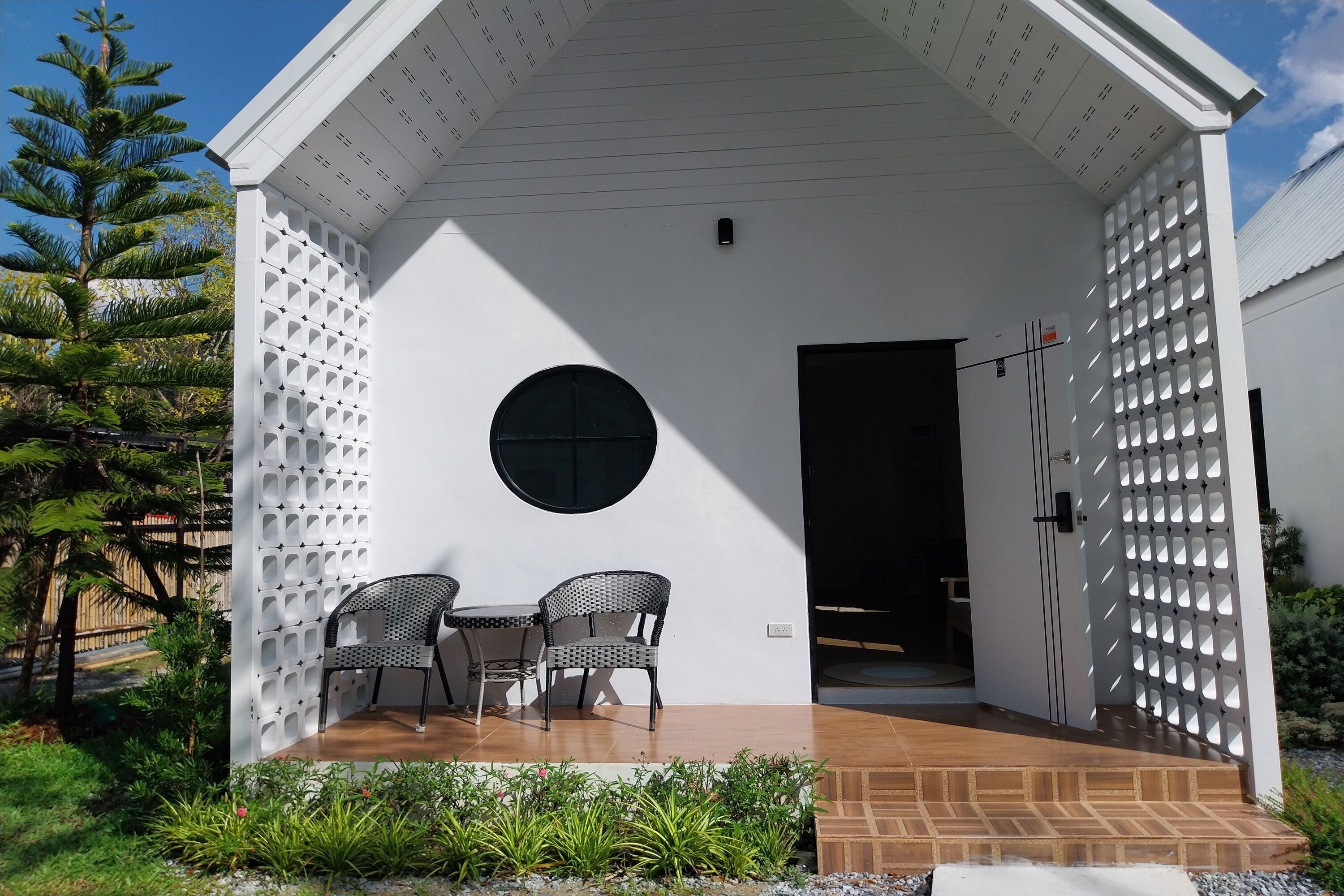 Un bâtiment moderne à l’extérieur blanc, doté d’une fenêtre circulaire et d’une porte.