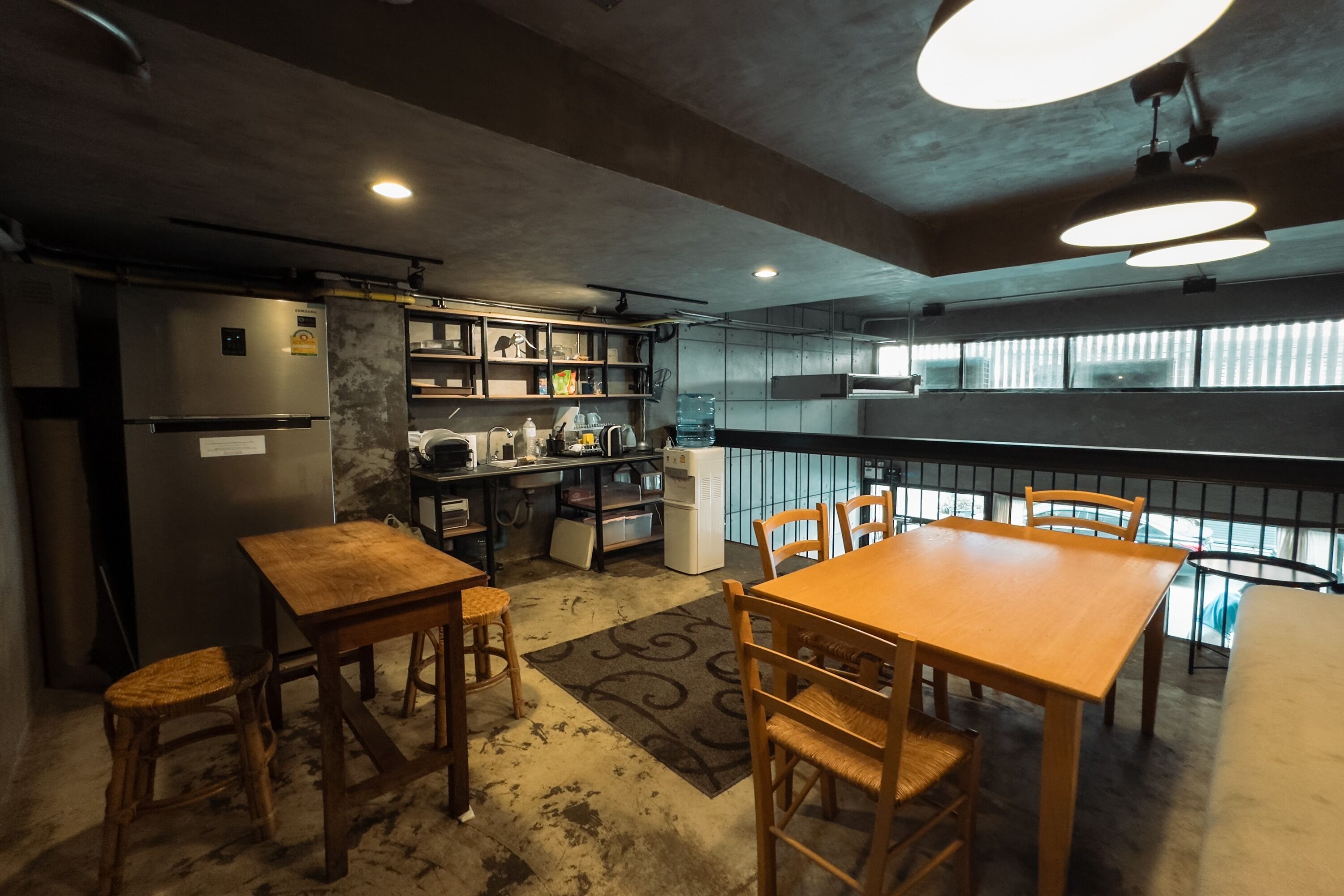 Una cocina compacta con refrigerador, estufa y estantes. Hay una mesa de comedor con sillas y una ventana con persianas.