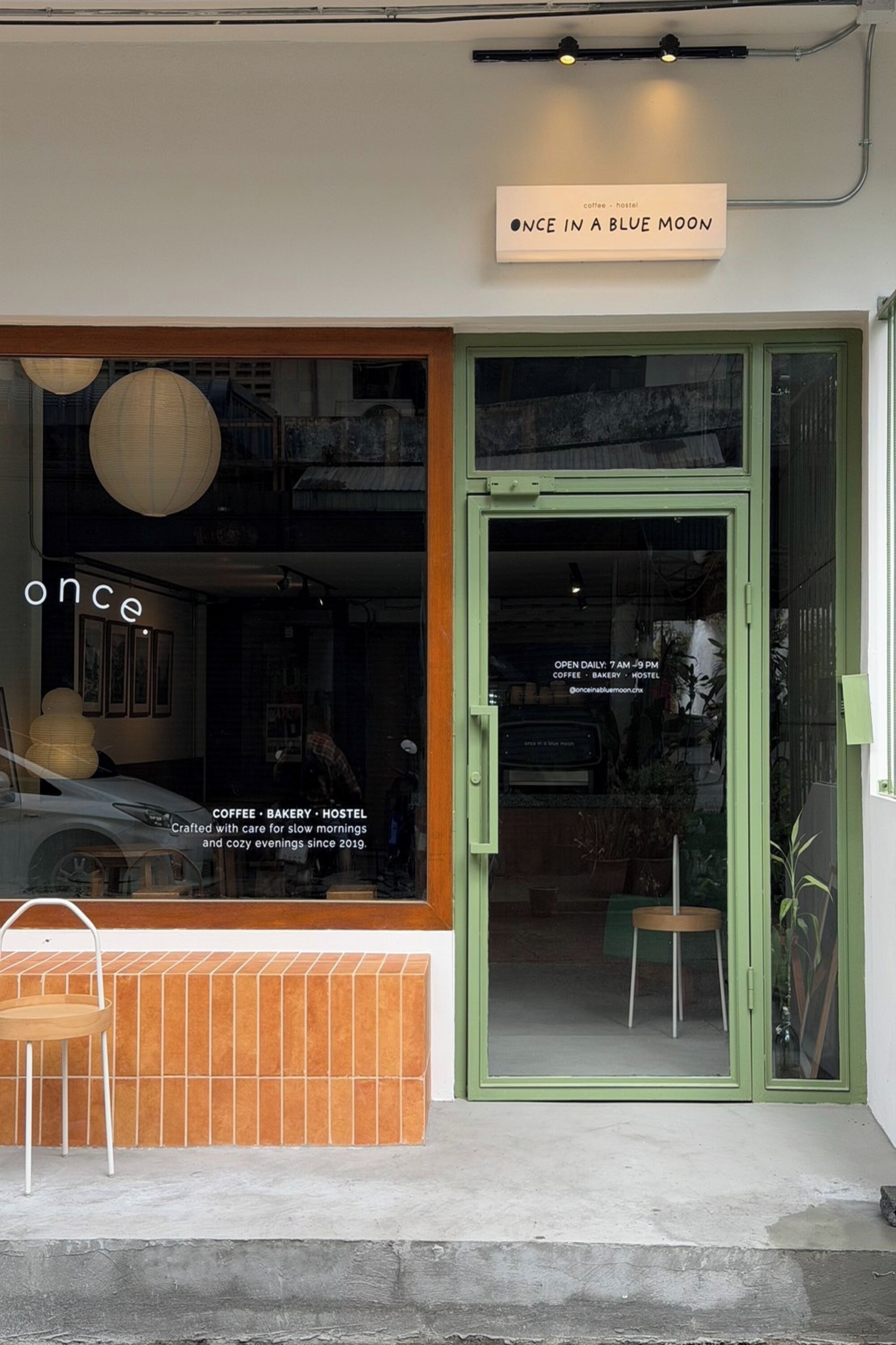 A storefront with a sign reading 'once in a blue moon' and a window displaying a car and interior furnishings.