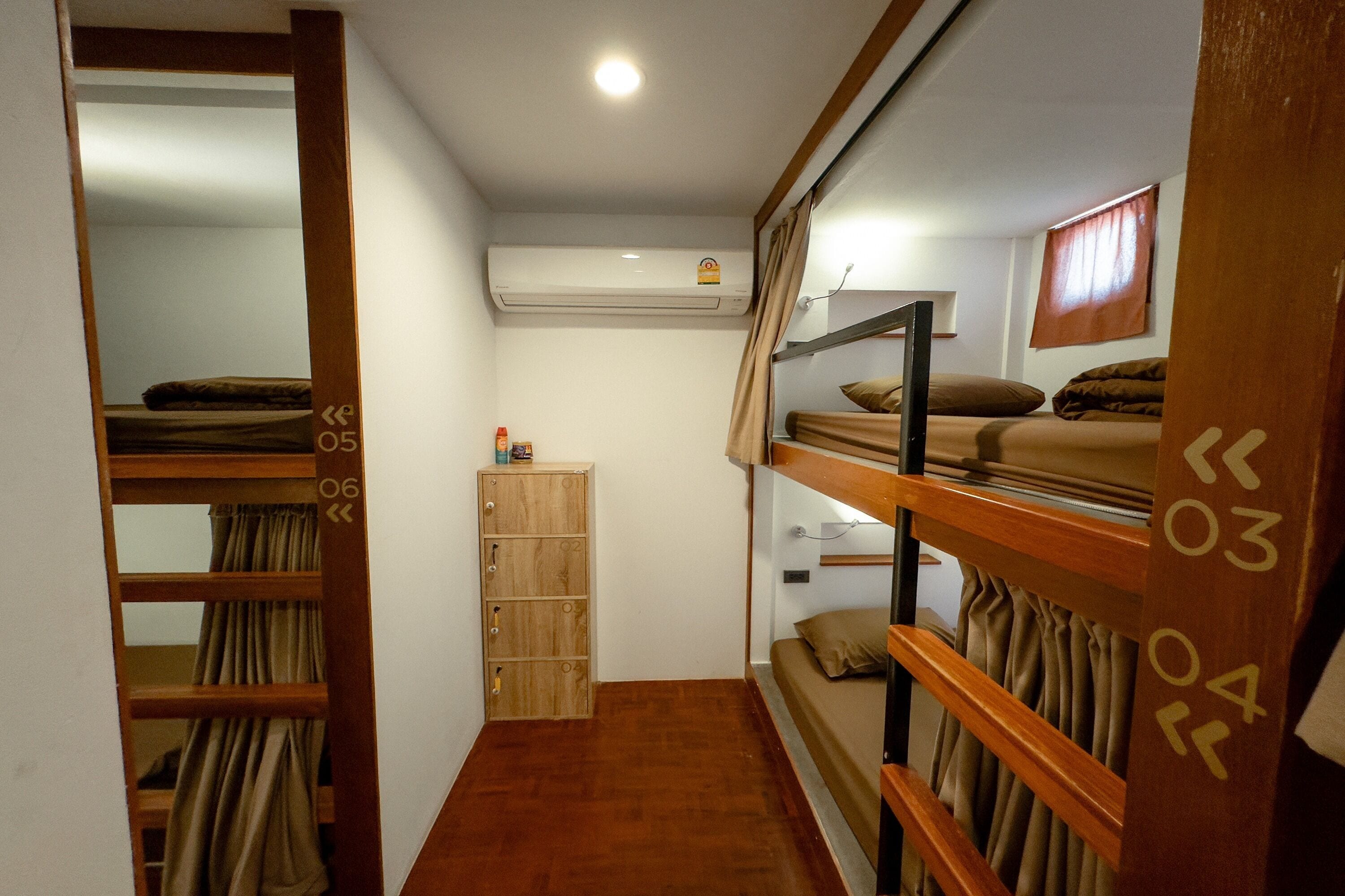 A compact room with bunk beds, a wooden wardrobe, and an air conditioning unit.
