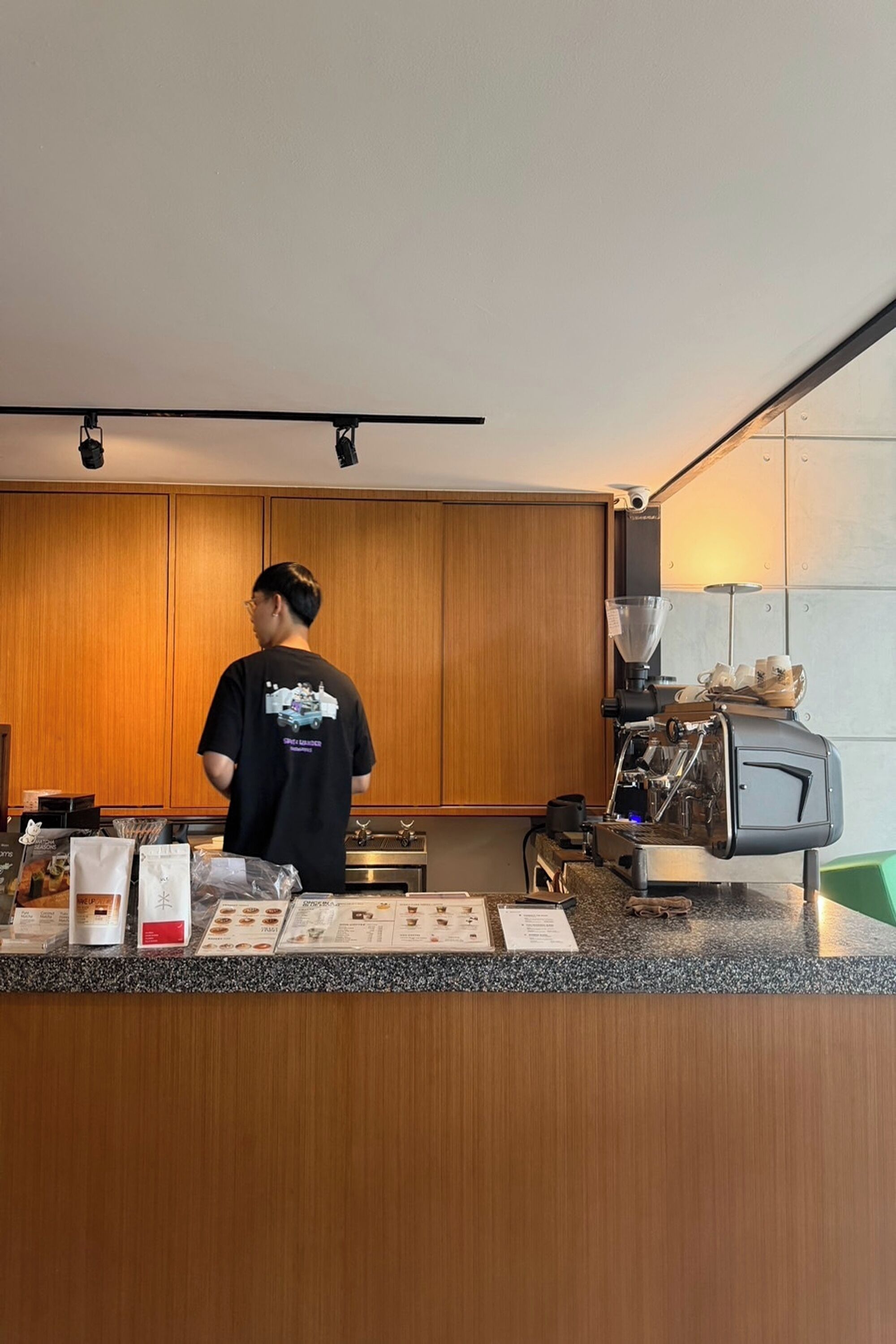 A person working at a counter with a coffee machine and menu items.