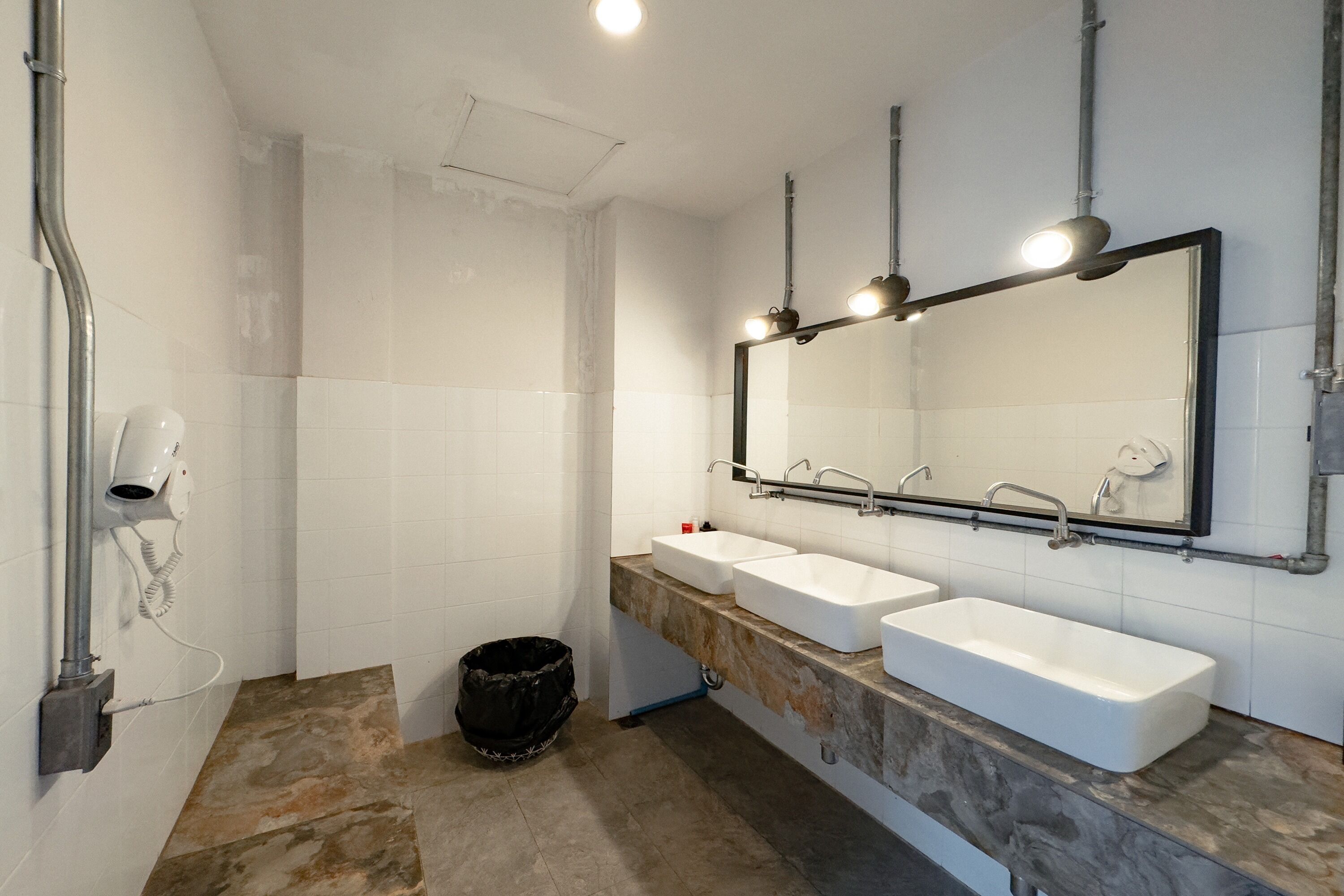 A modern bathroom with two sinks, a large mirror, and a hairdryer.
