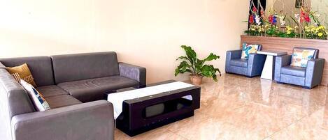 A modern lobby with a grey sofa, a small coffee table, and a blue armchair.