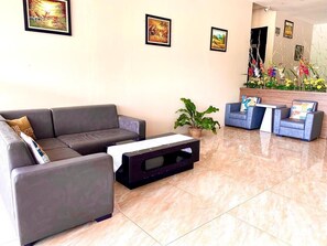 A modern lobby with a grey sofa, a small coffee table, and a blue armchair.