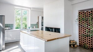 A modern kitchen with white cabinets, a wooden countertop, a built-in oven, and a large window.