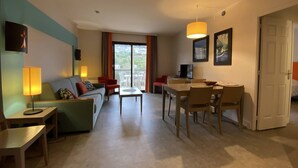 A modern hotel room with a living area, dining space, and a balcony with a view. - Stunning Beachfront Apartment with Pool, WiFi, and Balcony in Perros-Guirec (Perros-Guirec)