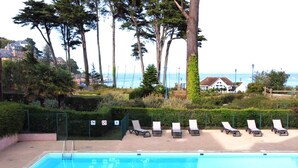 A swimming pool with lounge chairs and a view of the sea. - Stunning Beachfront Apartment with Pool, WiFi, and Balcony in Perros-Guirec (Perros-Guirec)
