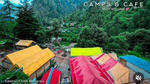 A campsite with multiple tents, a mountainous backdrop, and a contact number for booking. - Namste Kasol Camps (Bhuntar)