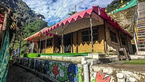 A building with a red roof and a colorful mural on the wall. - Namste Kasol Camps (Bhuntar)